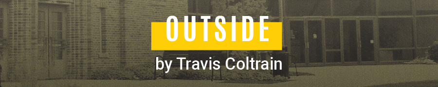Outside, written and directed by Travis Coltrain. Grey photo of theatre building.